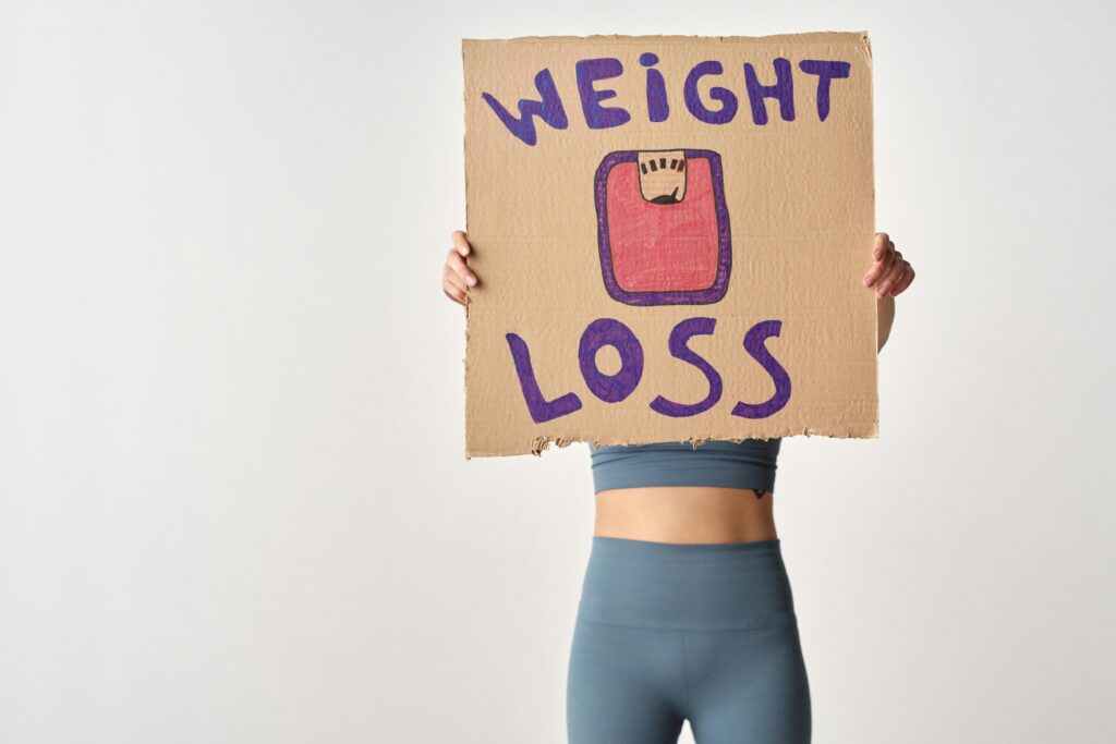 Person holding 'weight loss' sign for fitness motivation and health goals.